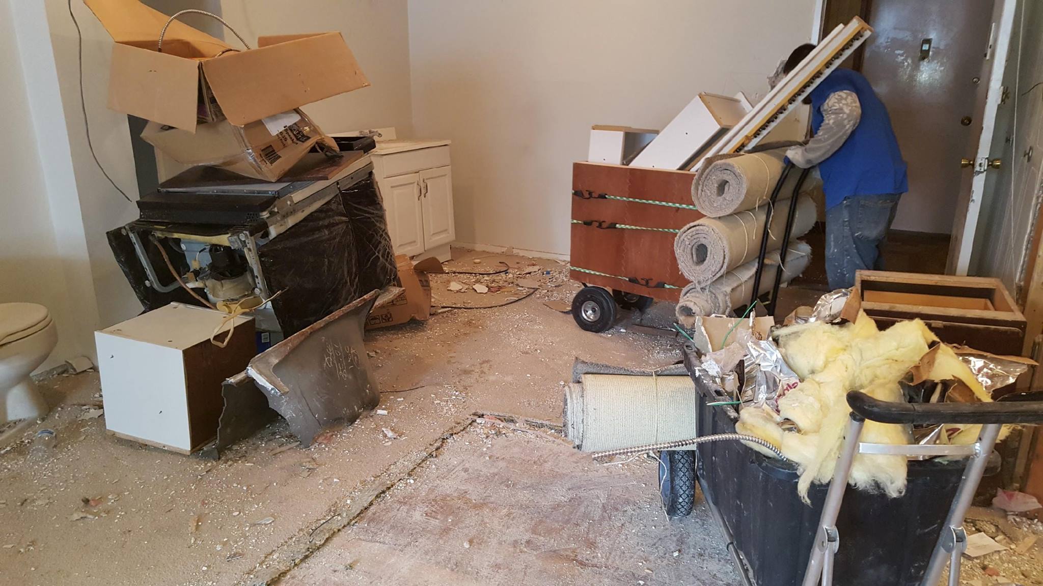Construction demolition debris being cleaned out including carpet rolls, cabinets, and appliances